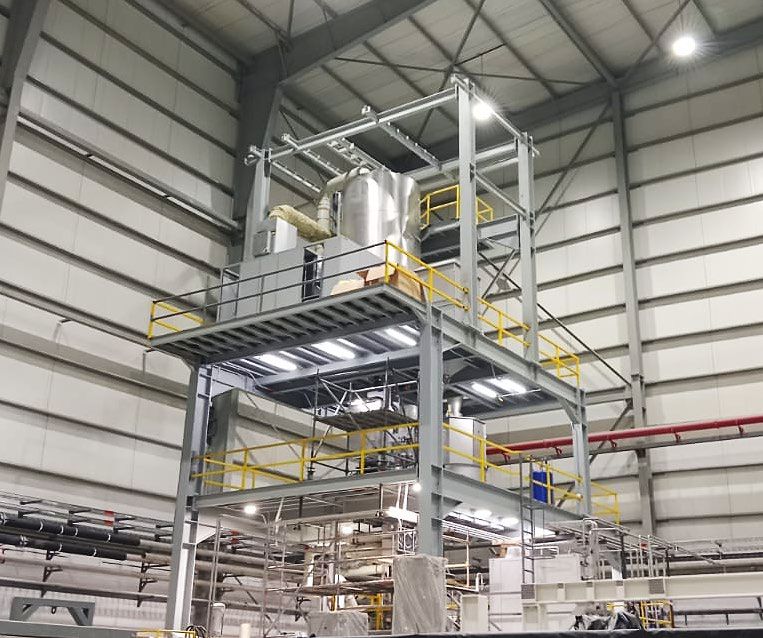 Estructura metálica industrial con plataformas, escaleras, barandas y equipos de proceso dentro de una planta.